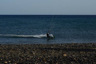 Bir uçurtma sörfçüsü, Matas Bay 'de, Matas de Blancas plajı boyunca sonbaharda Atlantik Okyanusu' nun dalgaları üzerinde sörf tahtasına biner. Uçurtma sörfü ya da uçurtma uçurmak rüzgar enerjisi gerektiren bir spordur. Costa Calma, Fuerteventura, Kanarya Adaları.  
