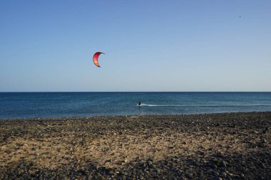 Bir uçurtma sörfçüsü, Matas Bay 'de, Matas de Blancas plajı boyunca sonbaharda Atlantik Okyanusu' nun dalgaları üzerinde sörf tahtasına biner. Uçurtma sörfü ya da uçurtma uçurmak rüzgar enerjisi gerektiren bir spordur. Costa Calma, Fuerteventura, Kanarya Adaları.  