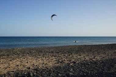 Bir uçurtma sörfçüsü, Matas Bay 'de, Matas de Blancas plajı boyunca sonbaharda Atlantik Okyanusu' nun dalgaları üzerinde sörf tahtasına biner. Uçurtma sörfü ya da uçurtma uçurmak rüzgar enerjisi gerektiren bir spordur. Costa Calma, Fuerteventura, Kanarya Adaları.  