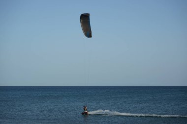 Bir uçurtma sörfçüsü, Matas Bay 'de, Matas de Blancas plajı boyunca sonbaharda Atlantik Okyanusu' nun dalgaları üzerinde sörf tahtasına biner. Uçurtma sörfü ya da uçurtma uçurmak rüzgar enerjisi gerektiren bir spordur. Costa Calma, Fuerteventura, Kanarya Adaları.  