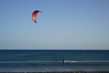 Bir uçurtma sörfçüsü, Matas Bay 'de, Matas de Blancas plajı boyunca sonbaharda Atlantik Okyanusu' nun dalgaları üzerinde sörf tahtasına biner. Uçurtma sörfü ya da uçurtma uçurmak rüzgar enerjisi gerektiren bir spordur. Costa Calma, Fuerteventura, Kanarya Adaları.  