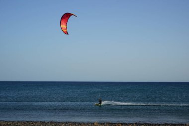 Bir uçurtma sörfçüsü, Matas Bay 'de, Matas de Blancas plajı boyunca sonbaharda Atlantik Okyanusu' nun dalgaları üzerinde sörf tahtasına biner. Uçurtma sörfü ya da uçurtma uçurmak rüzgar enerjisi gerektiren bir spordur. Costa Calma, Fuerteventura, Kanarya Adaları.  