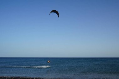 Bir uçurtma sörfçüsü, Matas Bay 'de, Matas de Blancas plajı boyunca sonbaharda Atlantik Okyanusu' nun dalgaları üzerinde sörf tahtasına biner. Uçurtma sörfü ya da uçurtma uçurmak rüzgar enerjisi gerektiren bir spordur. Costa Calma, Fuerteventura, Kanarya Adaları.  