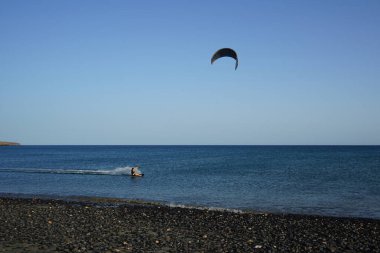 Bir uçurtma sörfçüsü, Matas Bay 'de, Matas de Blancas plajı boyunca sonbaharda Atlantik Okyanusu' nun dalgaları üzerinde sörf tahtasına biner. Uçurtma sörfü ya da uçurtma uçurmak rüzgar enerjisi gerektiren bir spordur. Costa Calma, Fuerteventura, Kanarya Adaları.  