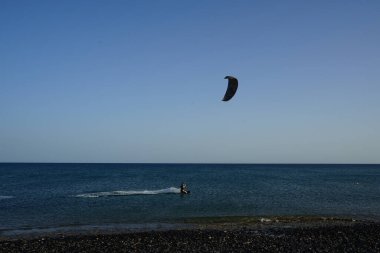 Bir uçurtma sörfçüsü, Matas Bay 'de, Matas de Blancas plajı boyunca sonbaharda Atlantik Okyanusu' nun dalgaları üzerinde sörf tahtasına biner. Uçurtma sörfü ya da uçurtma uçurmak rüzgar enerjisi gerektiren bir spordur. Costa Calma, Fuerteventura, Kanarya Adaları.  