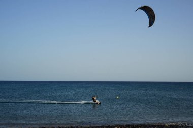 Bir uçurtma sörfçüsü, Matas Bay 'de, Matas de Blancas plajı boyunca sonbaharda Atlantik Okyanusu' nun dalgaları üzerinde sörf tahtasına biner. Uçurtma sörfü ya da uçurtma uçurmak rüzgar enerjisi gerektiren bir spordur. Costa Calma, Fuerteventura, Kanarya Adaları.  