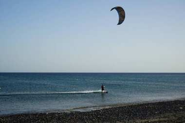 Bir uçurtma sörfçüsü, Matas Bay 'de, Matas de Blancas plajı boyunca sonbaharda Atlantik Okyanusu' nun dalgaları üzerinde sörf tahtasına biner. Uçurtma sörfü ya da uçurtma uçurmak rüzgar enerjisi gerektiren bir spordur. Costa Calma, Fuerteventura, Kanarya Adaları.  