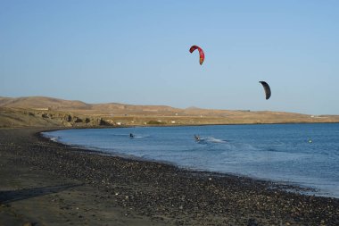Kiteboardcular sörf tahtalarını Matas Körfezi 'ndeki Atlantik Okyanusu' nun dalgalarından geçiriyorlar. Uçurtma sörfü ya da uçurtma uçurmak rüzgar enerjisi gerektiren bir spordur. Costa Calma, Fuerteventura, Las Palmas, Kanarya Adaları, İspanya. 