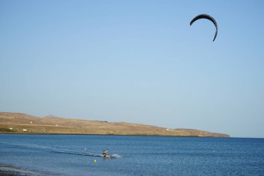 Bir uçurtma sörfçüsü, Matas Bay 'de, Matas de Blancas plajı boyunca sonbaharda Atlantik Okyanusu' nun dalgaları üzerinde sörf tahtasına biner. Uçurtma sörfü ya da uçurtma uçurmak rüzgar enerjisi gerektiren bir spordur. Costa Calma, Fuerteventura, Kanarya Adaları.  