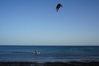 Bir uçurtma sörfçüsü, Matas Bay 'de, Matas de Blancas plajı boyunca sonbaharda Atlantik Okyanusu' nun dalgaları üzerinde sörf tahtasına biner. Uçurtma sörfü ya da uçurtma uçurmak rüzgar enerjisi gerektiren bir spordur. Costa Calma, Fuerteventura, Kanarya Adaları.  