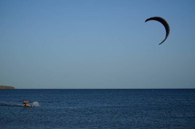 Bir uçurtma sörfçüsü, Matas Bay 'de, Matas de Blancas plajı boyunca sonbaharda Atlantik Okyanusu' nun dalgaları üzerinde sörf tahtasına biner. Uçurtma sörfü ya da uçurtma uçurmak rüzgar enerjisi gerektiren bir spordur. Costa Calma, Fuerteventura, Kanarya Adaları.  