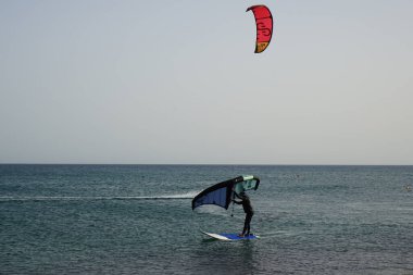 Matas Körfezi 'nde Atlantik Okyanusu' nun dalgalarında sörf tahtalarına binen bir uçurtma sörfçüsü ve bir kanat folyosu. Uçurtma sörfü ya da uçurtma uçurmak rüzgar enerjisi gerektiren bir spordur. Costa Calma, Fuerteventura, Las Palmas, İspanya. 