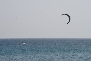 Bir uçurtma sörfçüsü, Matas Bay 'de, Matas de Blancas plajı boyunca sonbaharda Atlantik Okyanusu' nun dalgaları üzerinde sörf tahtasına biner. Uçurtma sörfü ya da uçurtma uçurmak rüzgar enerjisi gerektiren bir spordur. Costa Calma, Fuerteventura, Kanarya Adaları. 