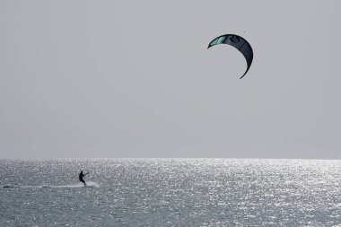 Bir uçurtma sörfçüsü, Matas Bay 'de, Matas de Blancas plajı boyunca sonbaharda Atlantik Okyanusu' nun dalgaları üzerinde sörf tahtasına biner. Uçurtma sörfü ya da uçurtma uçurmak rüzgar enerjisi gerektiren bir spordur. Costa Calma, Fuerteventura, Kanarya Adaları. 