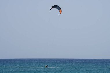 Bir uçurtma sörfçüsü, Matas Bay 'de, Matas de Blancas plajı boyunca sonbaharda Atlantik Okyanusu' nun dalgaları üzerinde sörf tahtasına biner. Uçurtma sörfü ya da uçurtma uçurmak rüzgar enerjisi gerektiren bir spordur. Costa Calma, Fuerteventura, Kanarya Adaları. 