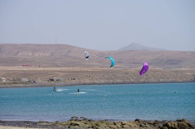 Kiteboardcular sörf tahtalarını Matas Körfezi 'ndeki Atlantik Okyanusu' nun dalgalarından geçiriyorlar. Uçurtma sörfü ya da uçurtma uçurmak rüzgar enerjisi gerektiren bir spordur. Costa Calma, Fuerteventura, Las Palmas, Kanarya Adaları, İspanya. 