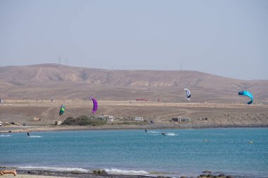 Kiteboardcular sörf tahtalarını Matas Körfezi 'ndeki Atlantik Okyanusu' nun dalgalarından geçiriyorlar. Uçurtma sörfü ya da uçurtma uçurmak rüzgar enerjisi gerektiren bir spordur. Costa Calma, Fuerteventura, Las Palmas, Kanarya Adaları, İspanya. 