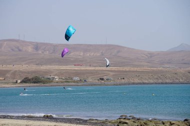 Kiteboardcular sörf tahtalarını Matas Körfezi 'ndeki Atlantik Okyanusu' nun dalgalarından geçiriyorlar. Uçurtma sörfü ya da uçurtma uçurmak rüzgar enerjisi gerektiren bir spordur. Costa Calma, Fuerteventura, Las Palmas, Kanarya Adaları, İspanya. 