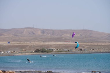Kiteboardcular sörf tahtalarını Matas Körfezi 'ndeki Atlantik Okyanusu' nun dalgalarından geçiriyorlar. Uçurtma sörfü ya da uçurtma uçurmak rüzgar enerjisi gerektiren bir spordur. Costa Calma, Fuerteventura, Las Palmas, Kanarya Adaları, İspanya. 