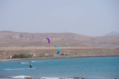 Kiteboardcular sörf tahtalarını Matas Körfezi 'ndeki Atlantik Okyanusu' nun dalgalarından geçiriyorlar. Uçurtma sörfü ya da uçurtma uçurmak rüzgar enerjisi gerektiren bir spordur. Costa Calma, Fuerteventura, Las Palmas, Kanarya Adaları, İspanya. 