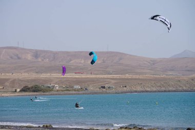 Kiteboardcular sörf tahtalarını Matas Körfezi 'ndeki Atlantik Okyanusu' nun dalgalarından geçiriyorlar. Uçurtma sörfü ya da uçurtma uçurmak rüzgar enerjisi gerektiren bir spordur. Costa Calma, Fuerteventura, Las Palmas, Kanarya Adaları, İspanya. 