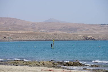 Bir rüzgar sörfçüsü, Matas Körfezi 'nde Atlantik Okyanusu' nun dalgalarında yelkenliyle sörf yapıyor. Rüzgâr sörfü, yelkencilik ve sörfün bir kombinasyonu olan rüzgar güdümlü bir su sporudur. Costa Calma, Fuerteventura, Las Palmas, Kanarya Adaları, İspanya.