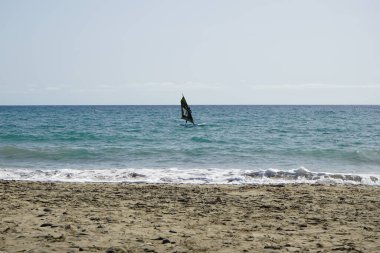 Bir rüzgar sörfçüsü, Matas Körfezi 'nde Atlantik Okyanusu' nun dalgalarında yelkenliyle sörf yapıyor. Rüzgâr sörfü, yelkencilik ve sörfün bir kombinasyonu olan rüzgar güdümlü bir su sporudur. Costa Calma, Fuerteventura, Las Palmas, Kanarya Adaları, İspanya.