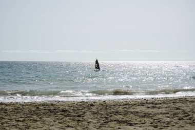 Bir rüzgar sörfçüsü, Matas Körfezi 'nde Atlantik Okyanusu' nun dalgalarında yelkenliyle sörf yapıyor. Rüzgâr sörfü, yelkencilik ve sörfün bir kombinasyonu olan rüzgar güdümlü bir su sporudur. Costa Calma, Fuerteventura, Las Palmas, Kanarya Adaları, İspanya.