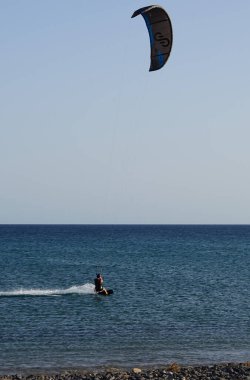 Bir uçurtma sörfçüsü, Matas Bay 'de, Matas de Blancas plajı boyunca sonbaharda Atlantik Okyanusu' nun dalgaları üzerinde sörf tahtasına biner. Uçurtma sörfü ya da uçurtma uçurmak rüzgar enerjisi gerektiren bir spordur. Costa Calma, Fuerteventura, Kanarya Adaları.  