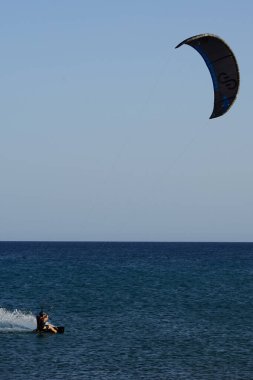 Bir uçurtma sörfçüsü, Matas Bay 'de, Matas de Blancas plajı boyunca sonbaharda Atlantik Okyanusu' nun dalgaları üzerinde sörf tahtasına biner. Uçurtma sörfü ya da uçurtma uçurmak rüzgar enerjisi gerektiren bir spordur. Costa Calma, Fuerteventura, Kanarya Adaları.  