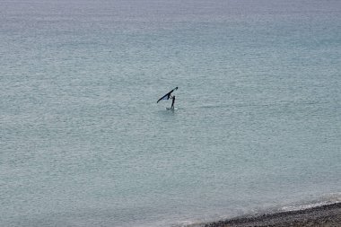 Bir kanat folyosu, Matas Körfezi 'ndeki Atlantik Okyanusu' nun dalgaları boyunca folyoyla yol alır. Kanat kanat çırpma, kanat çırpma veya kanat çırpma rüzgarı yakalamak için bir el kanadı kullanmayı ve suyun yüzeyinde bir levhayı itmeyi içerir. Costa Calma, İspanya.  