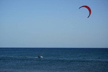 Bir uçurtma sörfçüsü, Matas Bay 'de, Matas de Blancas plajı boyunca sonbaharda Atlantik Okyanusu' nun dalgaları üzerinde sörf tahtasına biner. Uçurtma sörfü ya da uçurtma uçurmak rüzgar enerjisi gerektiren bir spordur. Costa Calma, Fuerteventura, Kanarya Adaları.  
