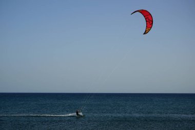 Bir uçurtma sörfçüsü, Matas Bay 'de, Matas de Blancas plajı boyunca sonbaharda Atlantik Okyanusu' nun dalgaları üzerinde sörf tahtasına biner. Uçurtma sörfü ya da uçurtma uçurmak rüzgar enerjisi gerektiren bir spordur. Costa Calma, Fuerteventura, Kanarya Adaları.  