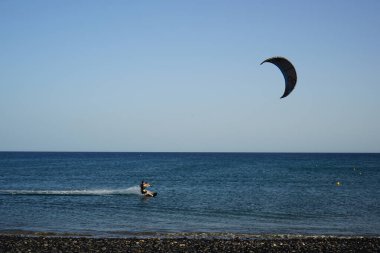 Bir uçurtma sörfçüsü, Matas Bay 'de, Matas de Blancas plajı boyunca sonbaharda Atlantik Okyanusu' nun dalgaları üzerinde sörf tahtasına biner. Uçurtma sörfü ya da uçurtma uçurmak rüzgar enerjisi gerektiren bir spordur. Costa Calma, Fuerteventura, Kanarya Adaları.  