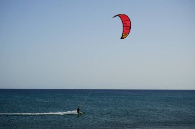 Bir uçurtma sörfçüsü, Matas Bay 'de, Matas de Blancas plajı boyunca sonbaharda Atlantik Okyanusu' nun dalgaları üzerinde sörf tahtasına biner. Uçurtma sörfü ya da uçurtma uçurmak rüzgar enerjisi gerektiren bir spordur. Costa Calma, Fuerteventura, Kanarya Adaları.  