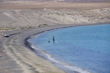 Bir rüzgar sörfçüsü, Matas Körfezi 'nde Atlantik Okyanusu' nun dalgalarında yelkenliyle sörf yapıyor. Rüzgâr sörfü, yelkencilik ve sörfün bir kombinasyonu olan rüzgar güdümlü bir su sporudur. Costa Calma, Fuerteventura, Las Palmas, Kanarya Adaları, İspanya. 