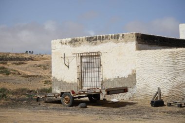 Atlantik kıyısındaki eski Rancho de Matas Blancas binasının önünde bir araba römorku duruyor. Costa Calma, Fuerteventura, Las Palmas, Kanarya Adaları, İspanya.