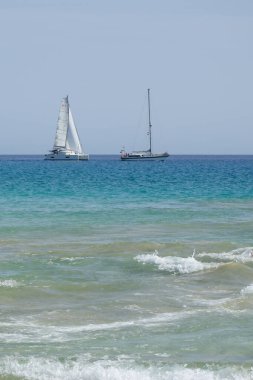 Ekim 'de Playa del Matorral plajı boyunca Atlantik Okyanusu' nda yelkenliler denize açılır. Morro Jable, Jandia, Fuerteventura, Las Palmas, Kanarya Adaları, İspanya. 