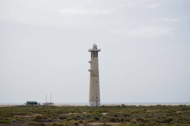 Ekim ayında, Morro Jable deniz feneri Faro de Morro Jable 'ın yanındaki Playa del Matorral plajı boyunca Atlantik Okyanusu' nda bir yelkenli yelken açılır. Solana Matorral, Morro Jable, Jandia, Fuerteventura, Las Palmas, Kanarya Adaları, İspanya. 