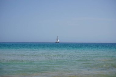 Atlantik Okyanusu 'nda, Playa del Matorral plajı boyunca, Ekim ayında, Fuerteventura, Las Palmas, Kanarya Adaları, İspanya' daki Morro Jable adasında bir yelkenli yatı seyreder..