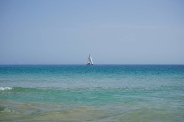 Atlantik Okyanusu 'nda, Playa del Matorral plajı boyunca, Ekim ayında, Fuerteventura, Las Palmas, Kanarya Adaları, İspanya' daki Morro Jable adasında bir yelkenli yatı seyreder..