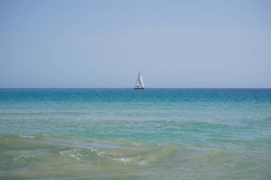 Atlantik Okyanusu 'nda, Playa del Matorral plajı boyunca, Ekim ayında, Fuerteventura, Las Palmas, Kanarya Adaları, İspanya' daki Morro Jable adasında bir yelkenli yatı seyreder..