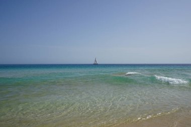 Atlantik Okyanusu 'nda, Playa del Matorral plajı boyunca, Ekim ayında, Fuerteventura, Las Palmas, Kanarya Adaları, İspanya' daki Morro Jable adasında bir yelkenli yatı seyreder..