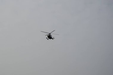 Bir helikopter, Tarajalejo tatil köyünün üstündeki bulutlu Ekim semalarında uçuyor. Helikopter, yatay dönen pervaneler tarafından desteklenen, kaldırma ve itme gücü olan bir rotorcraft türüdür. Tarajalejo, Tuineje, Fuerteventura, Kanarya Adaları. 