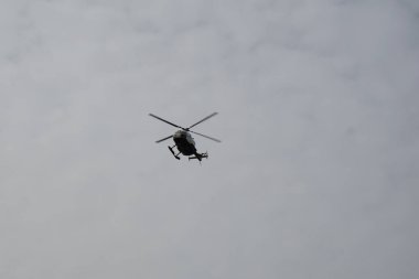 Bir helikopter, Tarajalejo tatil köyünün üstündeki bulutlu Ekim semalarında uçuyor. Helikopter, yatay dönen pervaneler tarafından desteklenen, kaldırma ve itme gücü olan bir rotorcraft türüdür. Tarajalejo, Tuineje, Fuerteventura, Kanarya Adaları. 