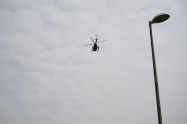 Bir helikopter, Tarajalejo tatil köyünün üstündeki bulutlu Ekim semalarında uçuyor. Helikopter, yatay dönen pervaneler tarafından desteklenen, kaldırma ve itme gücü olan bir rotorcraft türüdür. Tarajalejo, Tuineje, Fuerteventura, Kanarya Adaları. 