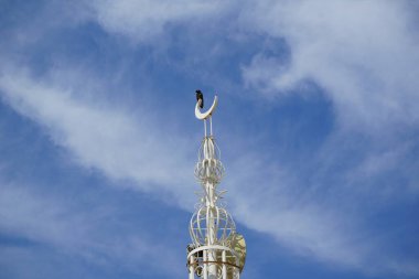 Tristis kuşu Nisan 'da ALBUSTAN MOSQUE' nin minaresinde oturur. Acridotheres tristis, Sturnidae familyasından bir kuş türü. Khor Fakkan, Sharjah, BAE. 