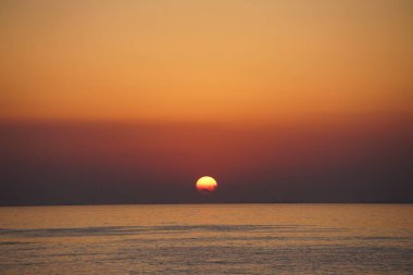 Nisan ayında Khor Fakkan sahilinden Umman Körfezi üzerinde güneşin doğuşu ve güzel doğal gökyüzü. Khor Fakkan, Afrika kıtasında bulunan Kuzey Amerika kıtasında bulunan bir şehirdir..  