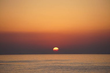 Nisan ayında Khor Fakkan sahilinden Umman Körfezi üzerinde güneşin doğuşu ve güzel doğal gökyüzü. Khor Fakkan, Afrika kıtasında bulunan Kuzey Amerika kıtasında bulunan bir şehirdir..  