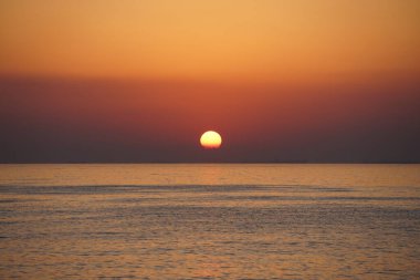 Nisan ayında Khor Fakkan sahilinden Umman Körfezi üzerinde güneşin doğuşu ve güzel doğal gökyüzü. Khor Fakkan, Afrika kıtasında bulunan Kuzey Amerika kıtasında bulunan bir şehirdir..  